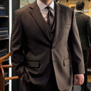 A man wearing brown suit and trousers with a white shirt and matching colour 
