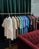 Albini linen shirts neatly arranged on hanger rack - colourful, breathable fabrics for summer wardrobes.