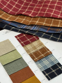 Stack of plaid fabric swatches in variety of patterns and colours.