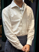 Person wearing a beige long-sleeve shirt over a white scarf
