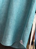Close-up of a teal fabric with a Albini label made from high quality European linen.