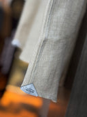 Close-up of a beige shirts with a brand label showing linen textures.
