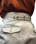 Light-colored pants with a back buckle design and horn buttons details.