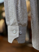 Close-up of a beige textured shirt with mother of pearl buttons.