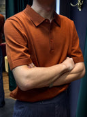 Person wearing a brown polo shirt with arms crossed