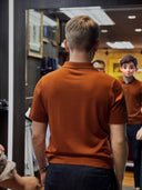 Person wearing an orange red polo shirt in WH Bespoke fitting room