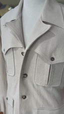 Close-up of a light beige coat with textured fabric and button details.